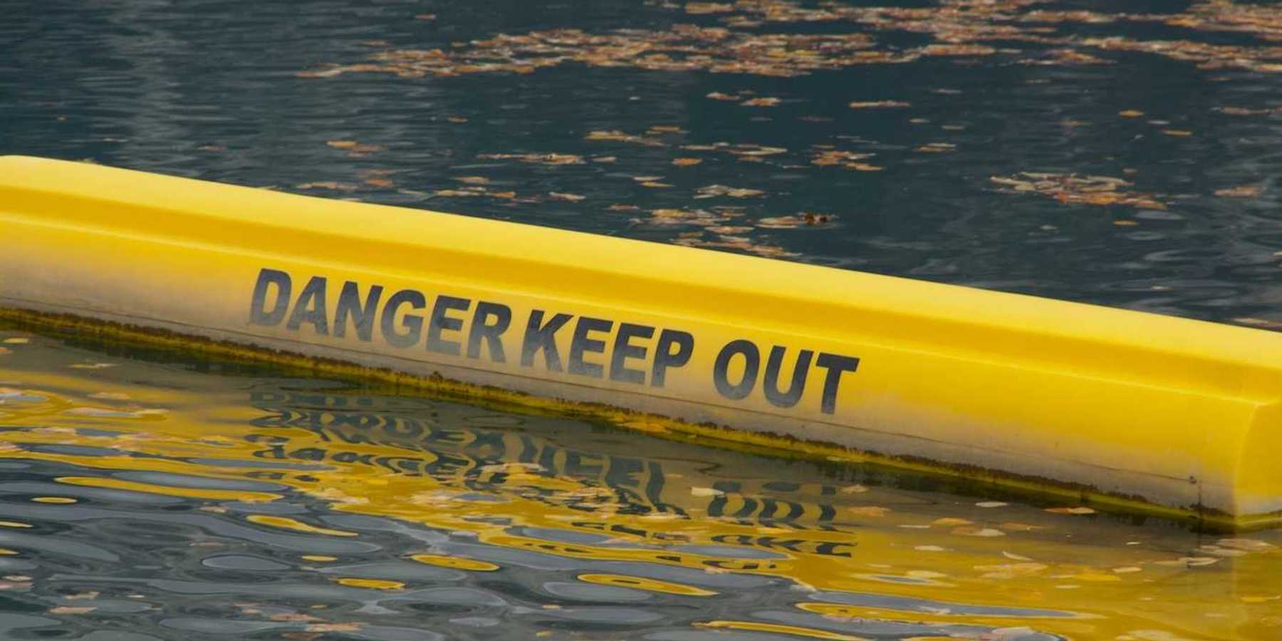 Yellow floating water barrier reading "DANGER KEEP OUT"