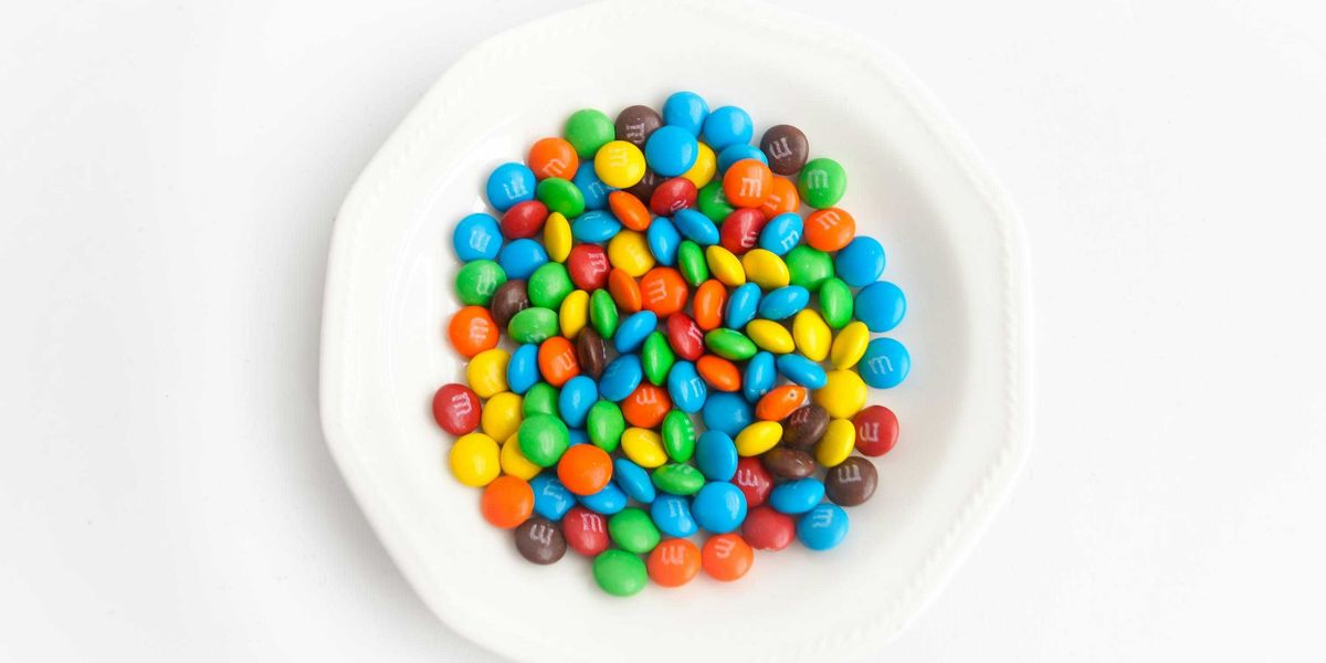 yellow green  blue and red candies on white ceramic round plate.