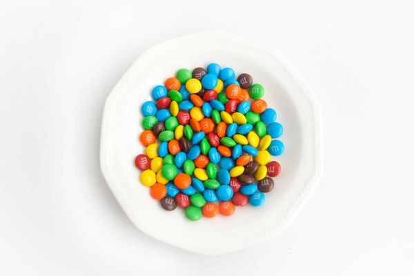 yellow green  blue and red candies on white ceramic round plate.