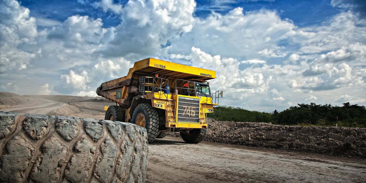 yellow mining truck on dirt road during daytime.