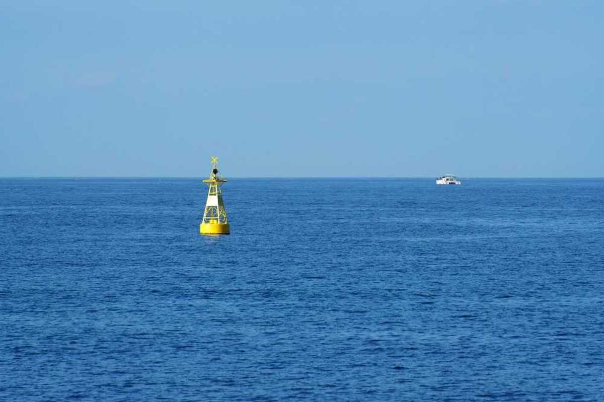 Yellow ocean monitoring buoy with an unidentified white boat nearby