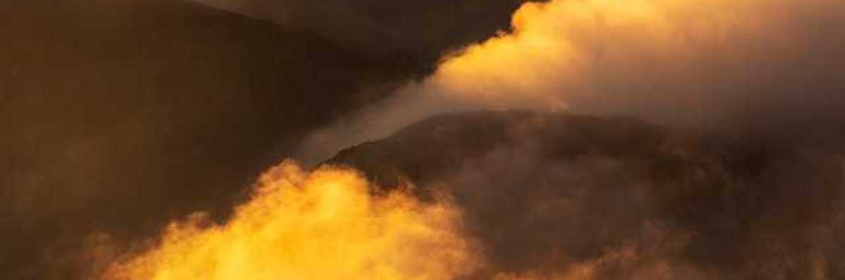 Yellow smoke billowing out of valleys in between mountains