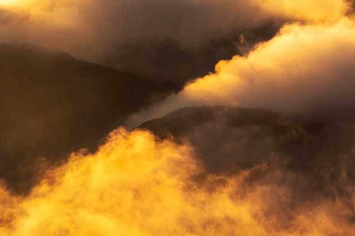 Yellow smoke billowing out of valleys in between mountains