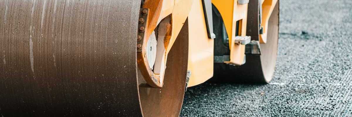 Yellow "Steam roller" compressing fresh asphalt