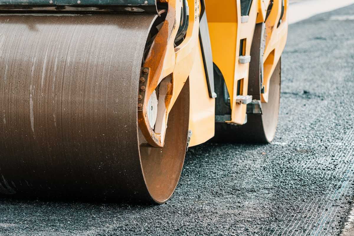 Yellow "Steam roller" compressing fresh asphalt