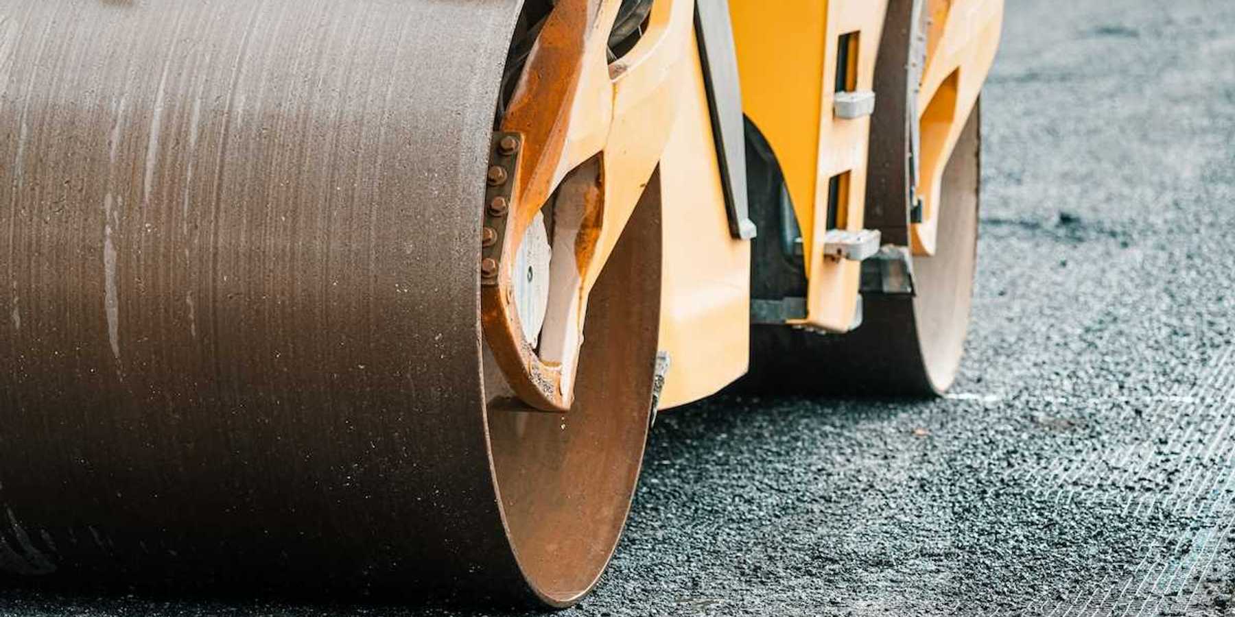 Yellow "Steam roller" compressing fresh asphalt