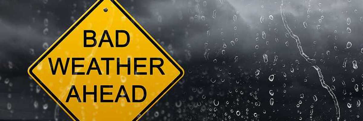 Yellow warning sign of bad weather ahead against stormy sky