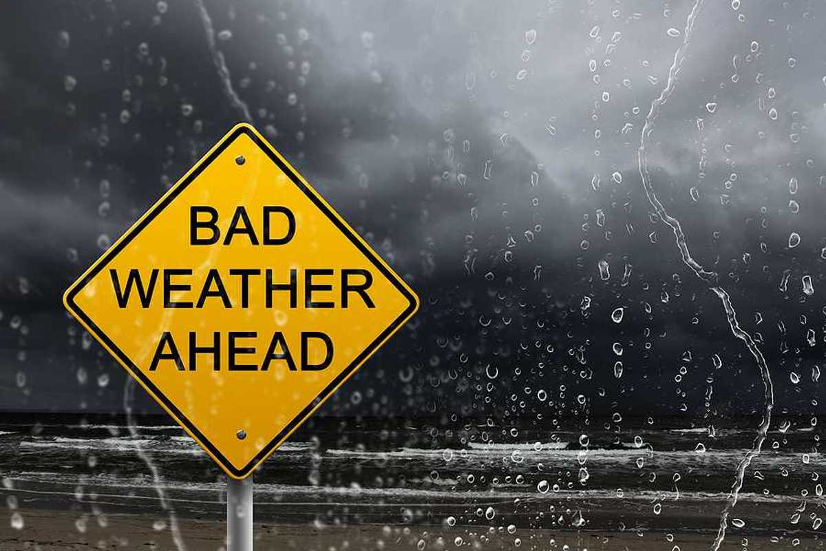 Yellow warning sign of bad weather ahead against stormy sky