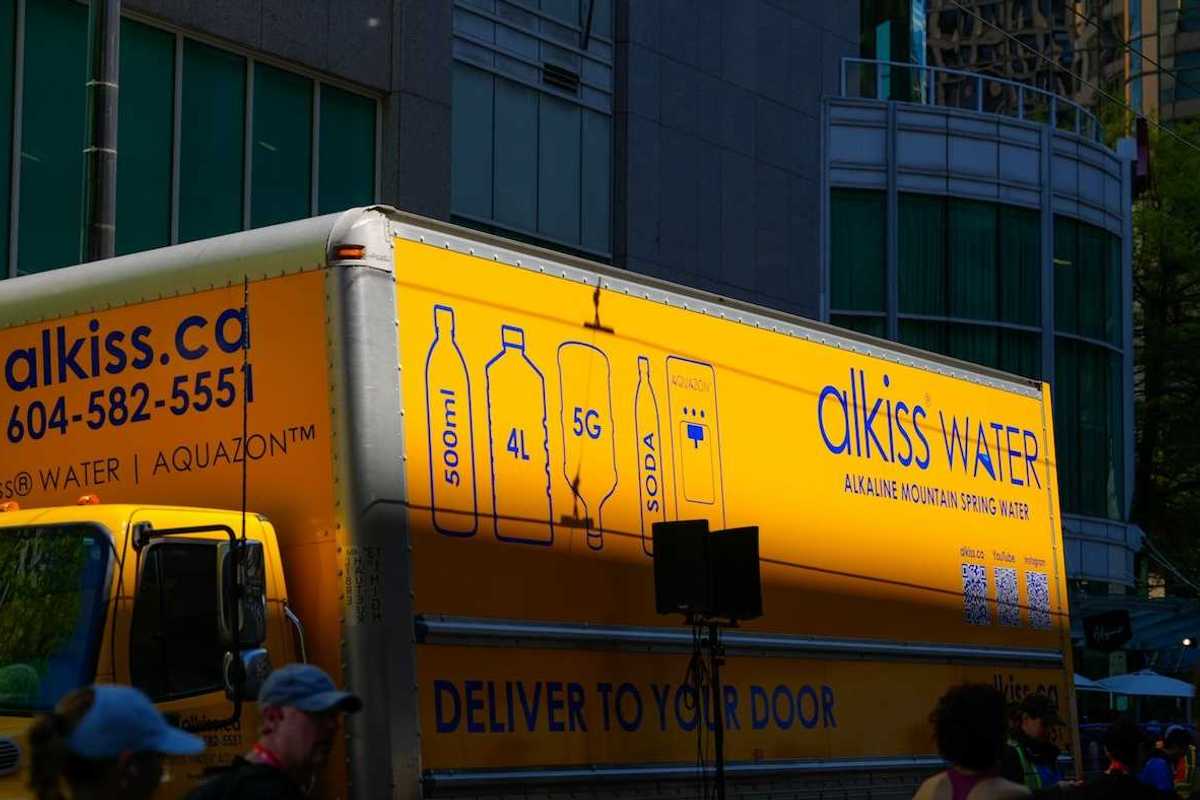 Yellow water delivery truck: "alkiss water. DELIVER TO YOUR DOO"