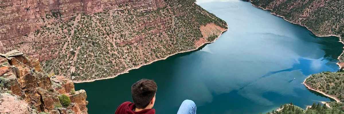 Young man seated on a rock outcrop overlooking Flaming Gorge reservoir