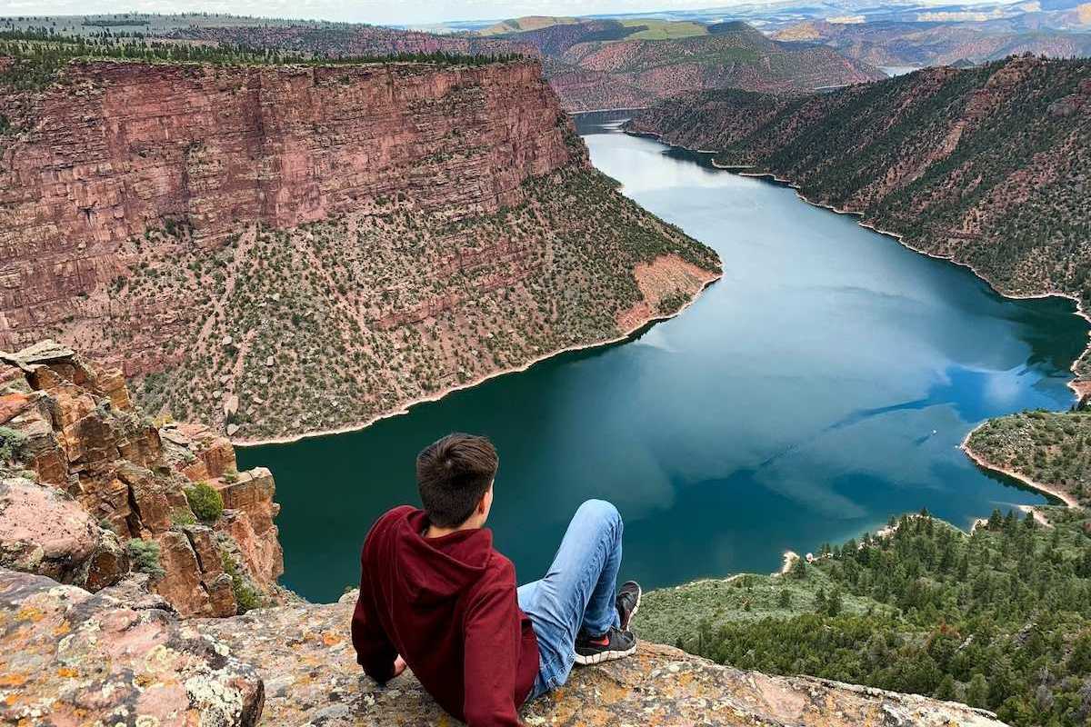 Young man seated on a rock outcrop overlooking Flaming Gorge reservoir