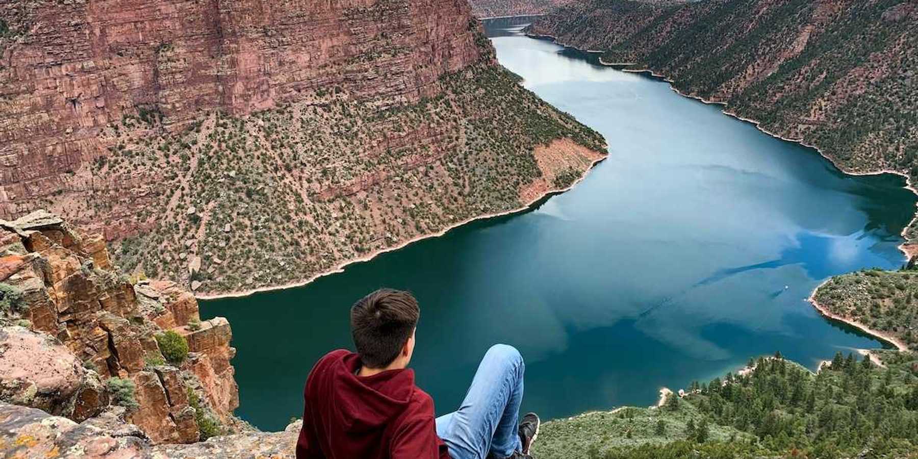 Young man seated on a rock outcrop overlooking Flaming Gorge reservoir