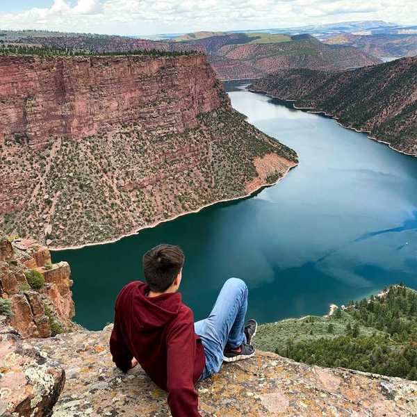 Young man seated on a rock outcrop overlooking Flaming Gorge reservoir